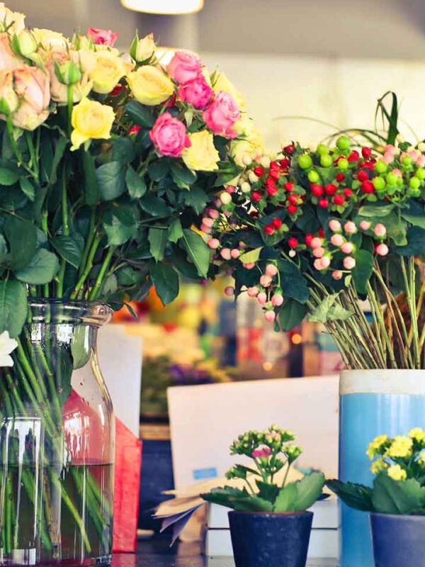 Jarrones con rosas, hypericum y gerberas en el mostrador