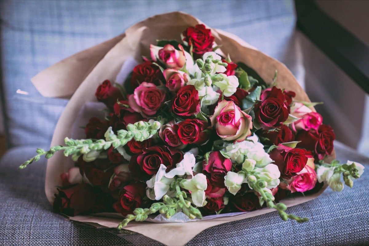 Ramo de rosas rojas y bicolores con antirrinos blancos en papel kraft